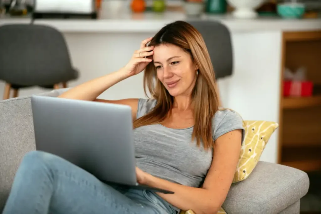 A woman comfortably sitting on a couch, engaged with her laptop, illustrating a blend of relaxation and work